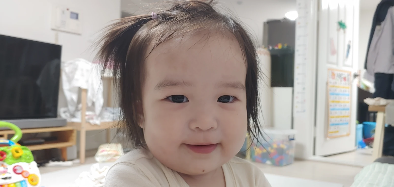 작은 머리 묶음을 하고 카메라를 보며 웃는 윤슬이
